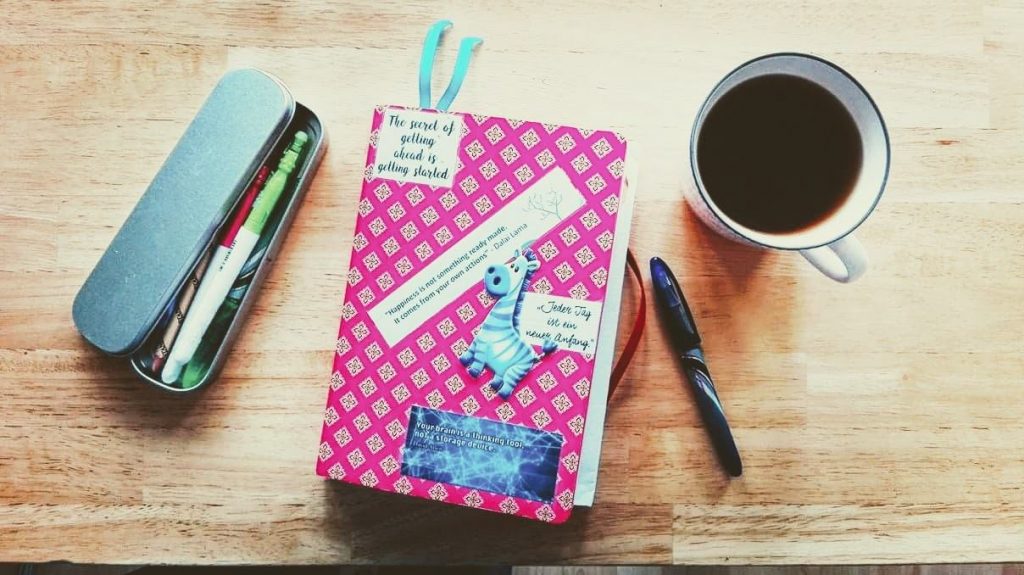 Buch, Stifte und Tasse auf einem Tisch