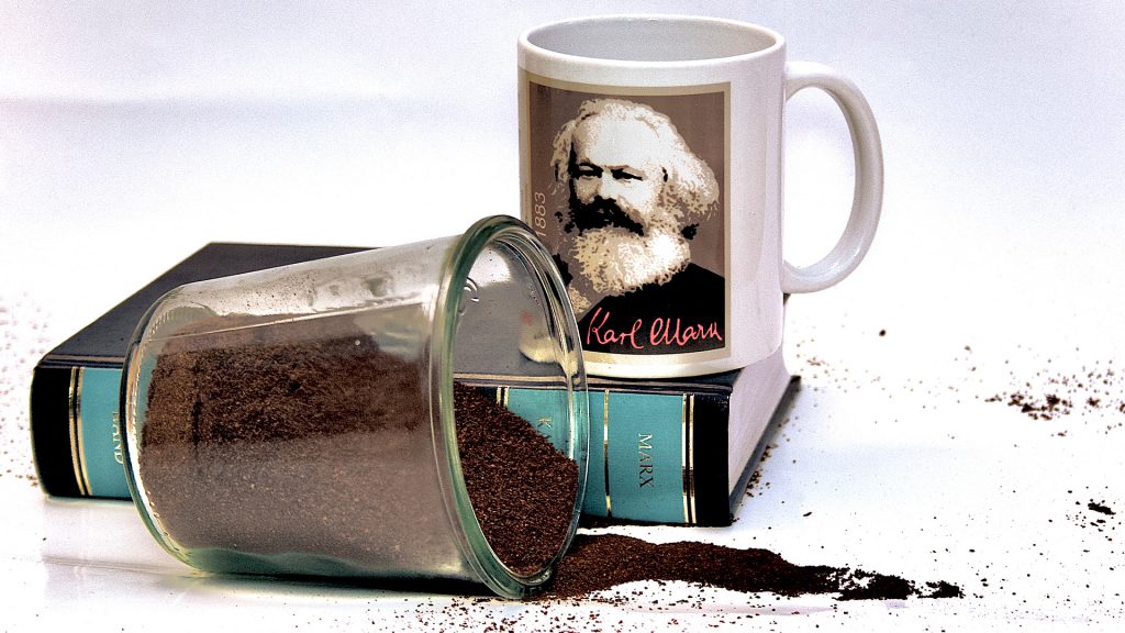 Kaffetasse mit Bild von Karl Marx, davor auslaufendes Kaffepulver