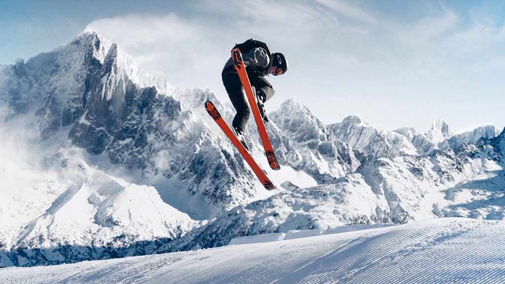 Skifahrer in der Luft, im Hintergrund Berge