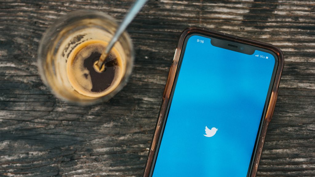 Handy mit Twitter Logo und Kaffeeglas auf einem Holztisch