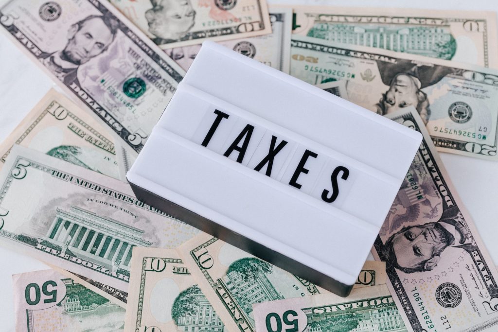 Schriftzug "Taxes" inmitten von Geldscheinen