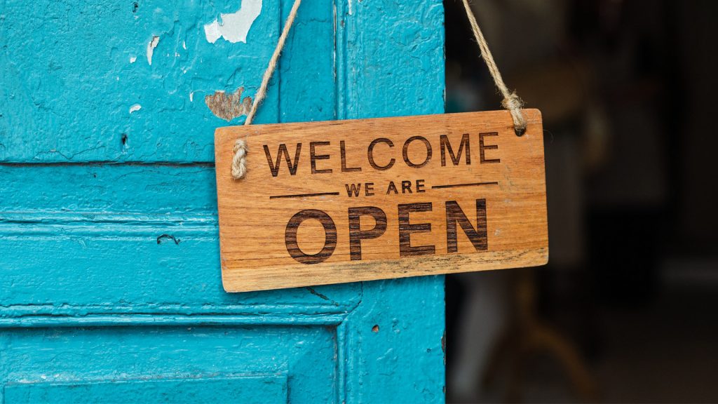 Schild an einer Tür: Welcome, we are open