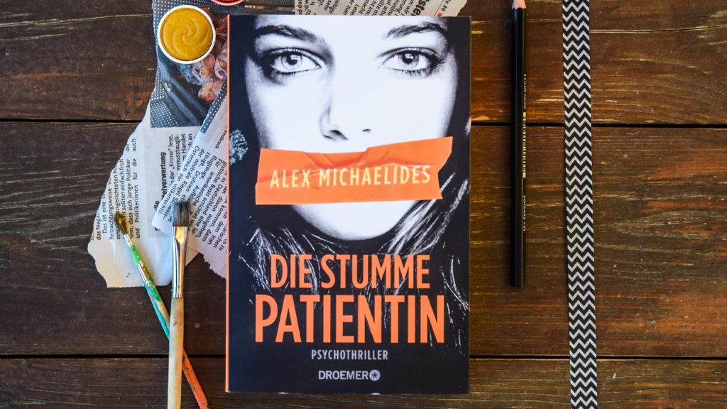 Das Buch "Die stumme Patientin" auf einem Holztisch liegend