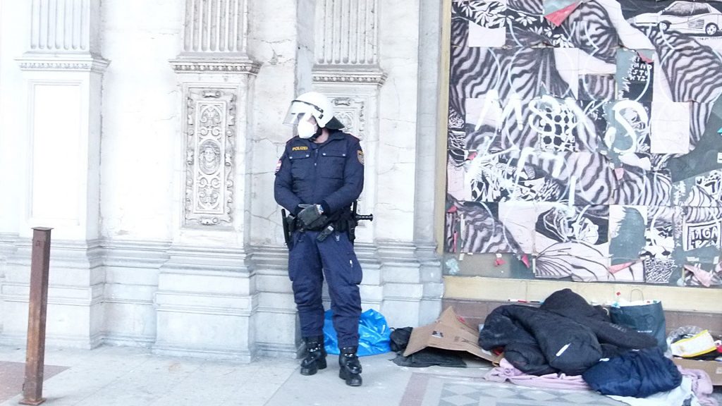 Polizist steht vor einer Häuserwand