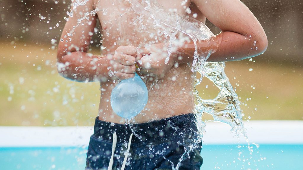 Kind mit Wasserbombe in Pool