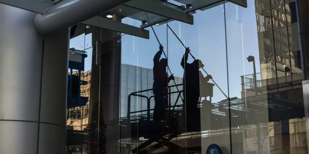 Menschen, die die Fenster einen großen Gebäudes putzen, man sieht ihre Schatten