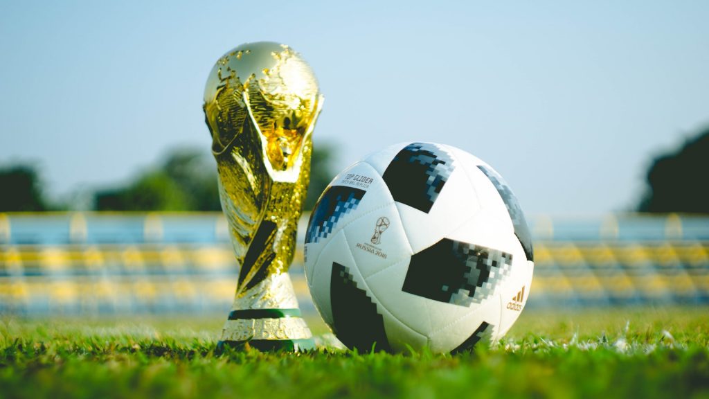 WM-Pokal und schwarz-weißer Fußball auf dem Rasen