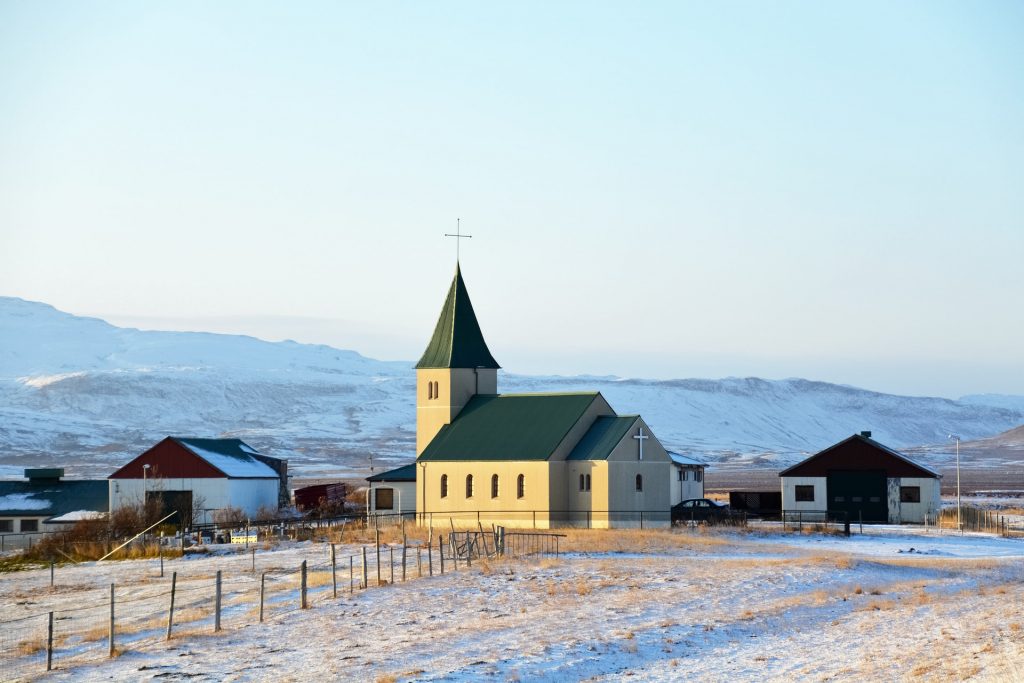 Kirche im Sonnenlicht, daneben kleine Häuser