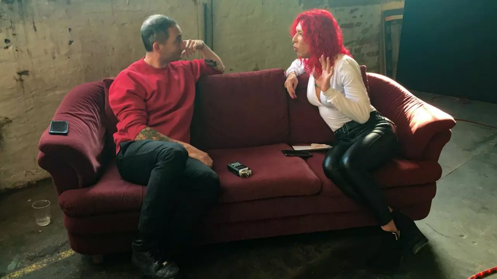 Ein Mann und eine Frau sitzen auf einer schwarzen Couch und unterhalten sich