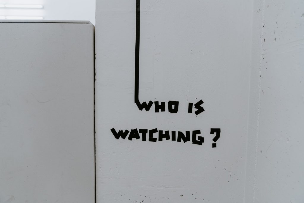 Schrift "Who is watchign" auf weißem Hintergrund