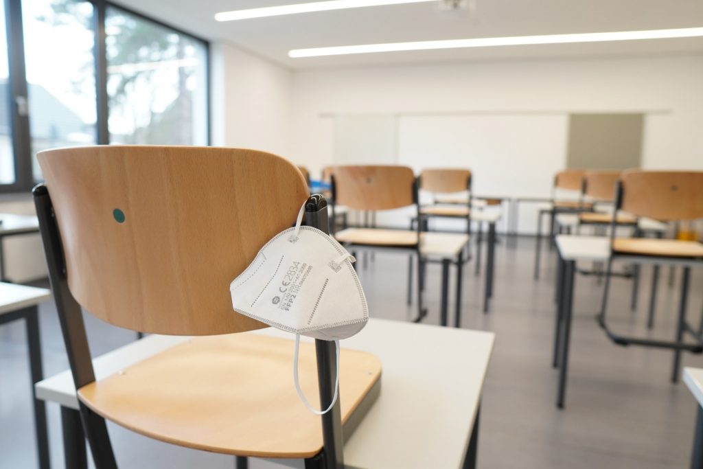 FFP2-Maske hängt auf einem Sessel in einem leeren Klassenraum