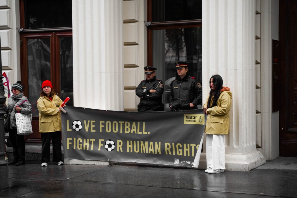 Aktivist*innen von Amnesty halten Transparent mit Aufschrift: Love Football, Fight For Human Rights