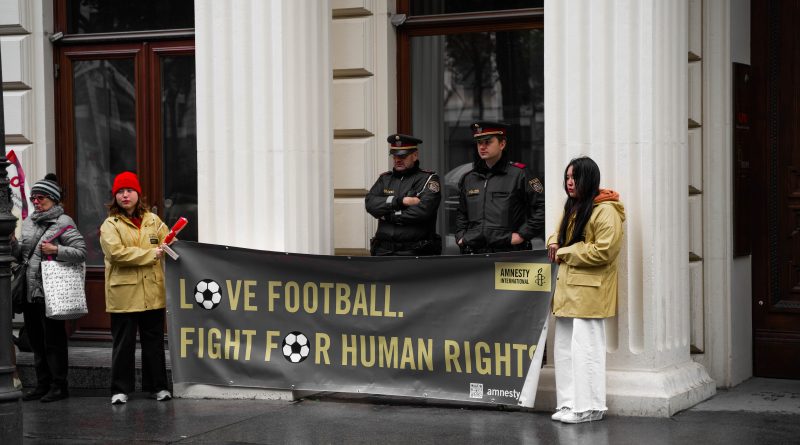 Aktivist*innen von Amnesty halten Transparent mit Aufschrift: Love Football, Fight For Human Rights