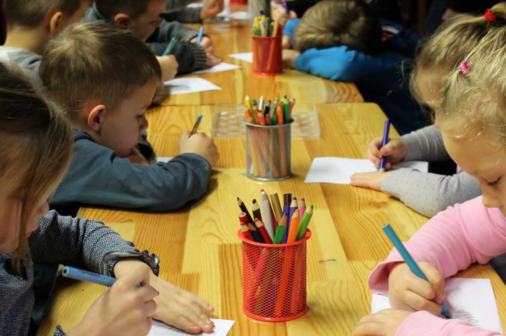 Kinder sitzen an einem Tisch und malen
