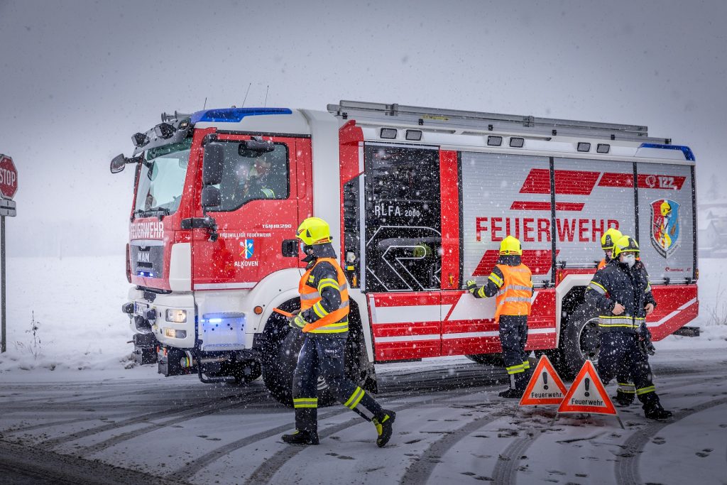 Feuerwehrauto und Feuerwehrleute im Schneegestöber