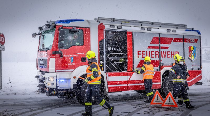 Feuerwehrauto und Feuerwehrleute im Schneegestöber