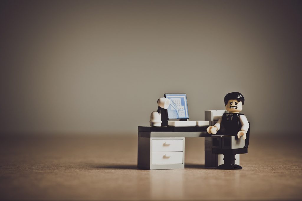 Legofigur sitz am Schreibtisch mit verzweifeltem Gesicht