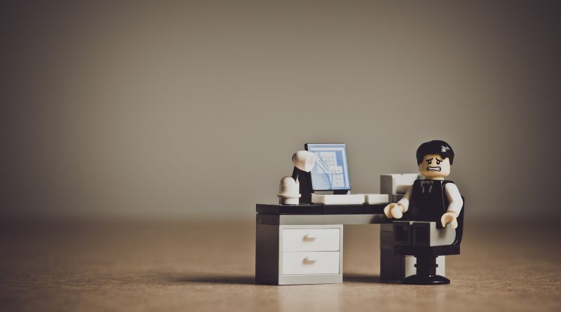 Legofigur sitz am Schreibtisch mit verzweifeltem Gesicht