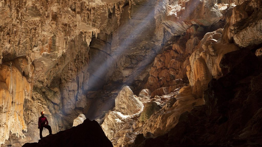 Person steht in einer Höhle, in die ein Sonnenstrahl scheint