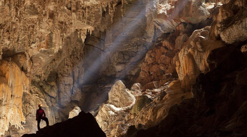 Person steht in einer Höhle, in die ein Sonnenstrahl scheint