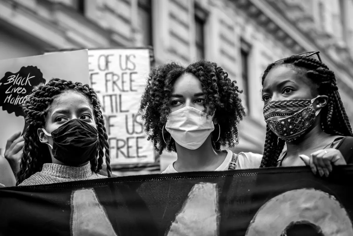 Drei Schwarze Frauen mit Maske bei einer Demo