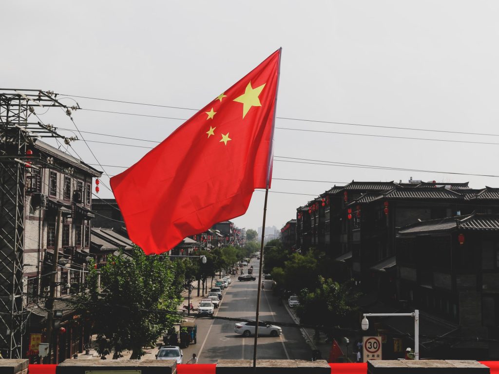 Flagge von China, dahinter eine Straße mit Häuser