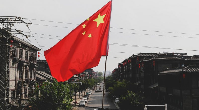 Flagge von China, dahinter eine Straße mit Häuser