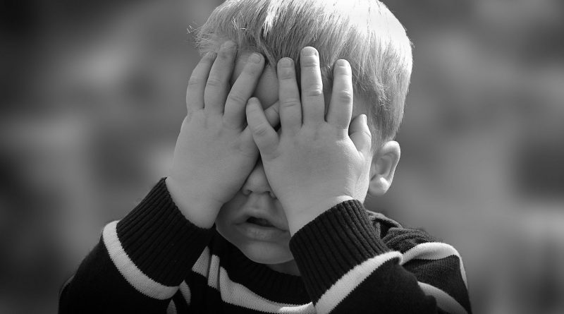 Kleines Kind bedeckt das Gesicht mit seinen Händen, schwarz-weiß-Foto