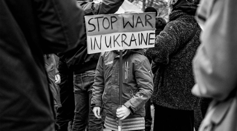 Kind hält Demoschild mit der Aufschrift "Stop Wat in Ukraine"