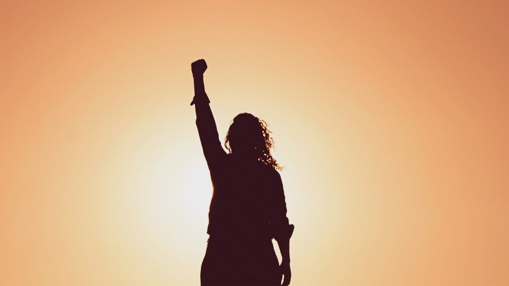 Silhouette einer Frau mit Power Pose, Hintergrund orange