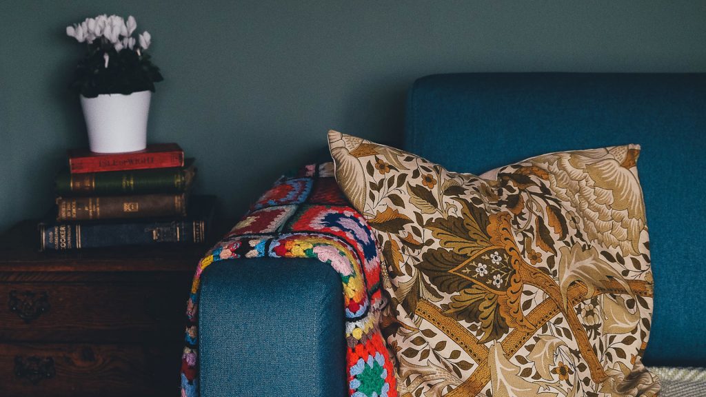 Polster auf einer Couch, links Blumen