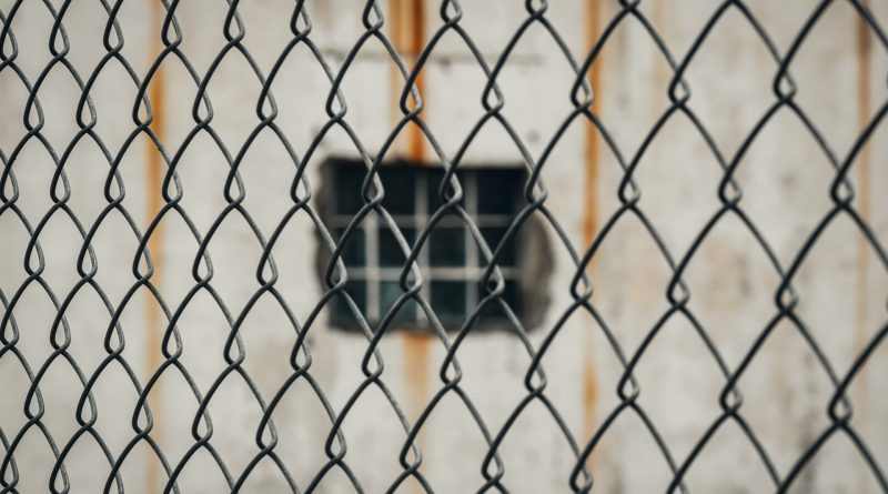 Gefängnisfenster hinter einem Maschendrahtzaun