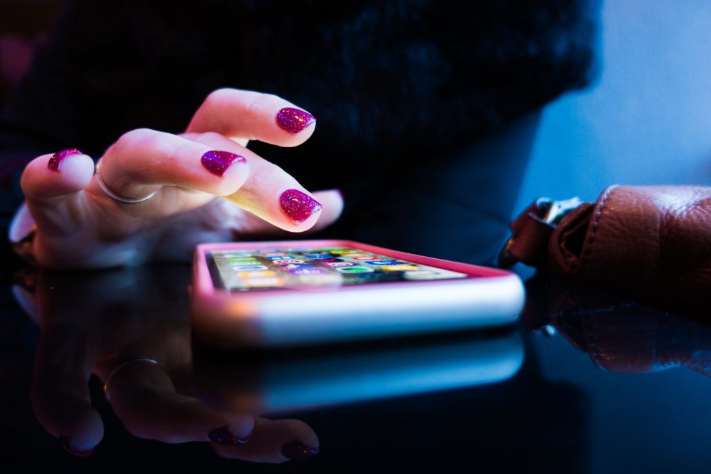 Person mit lackierten Fingernägeln tippt auf einem Smartphone