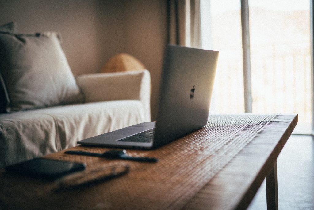 offener Apple-Laptop auf einem Holztisch vor einer hellen Couch
