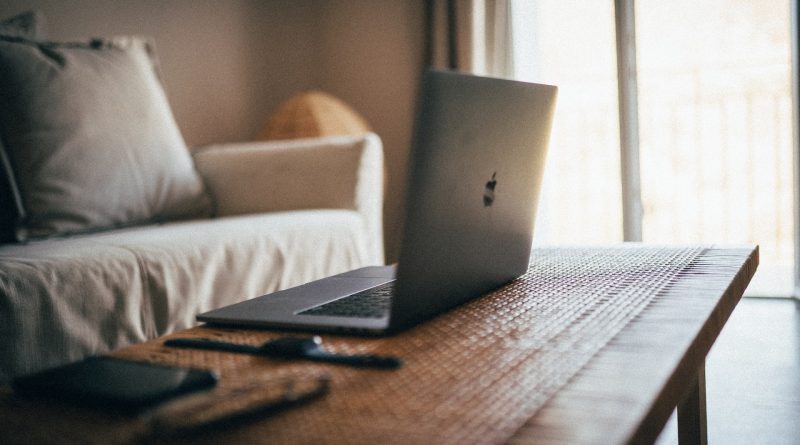 offener Apple-Laptop auf einem Holztisch vor einer hellen Couch