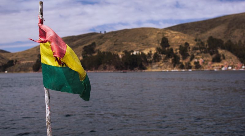 Flagge von Bolivien auf einem Boot, dahinter Wasser