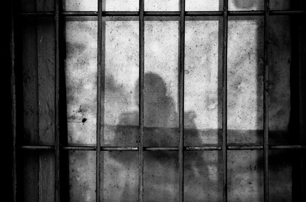 Schatten einer Person auf einer Wand mit Gitterstäben