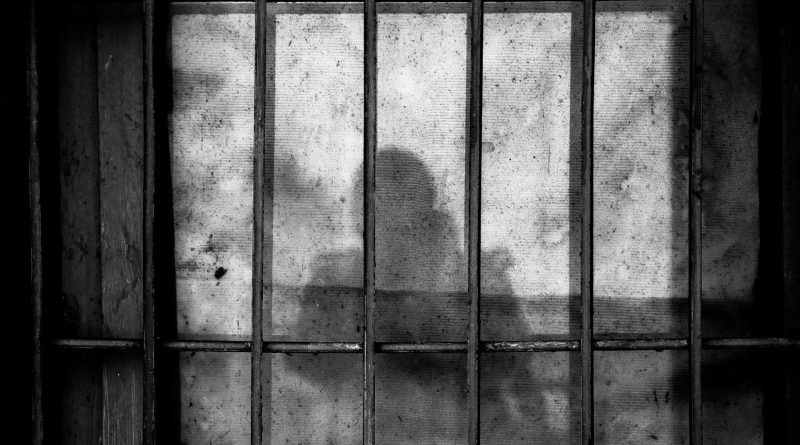 Schatten einer Person auf einer Wand mit Gitterstäben