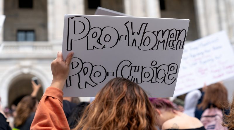 Person hält weißes Schild mit Aufschrift "Pro Women, Pro Choice" in die Höhe, von hinten fotografiert