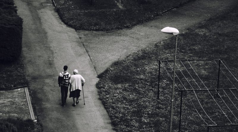 Junge Person mit Rucksack geht mit alter Person spazieren, Foto von oben