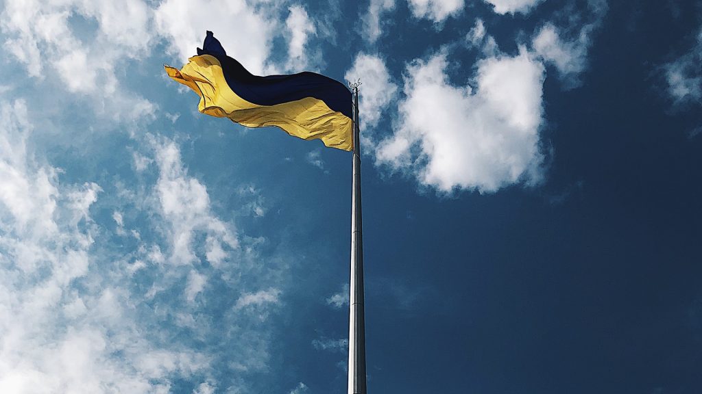 Ukrainische Flagge auf Fahnenmast vor blauem Himmel