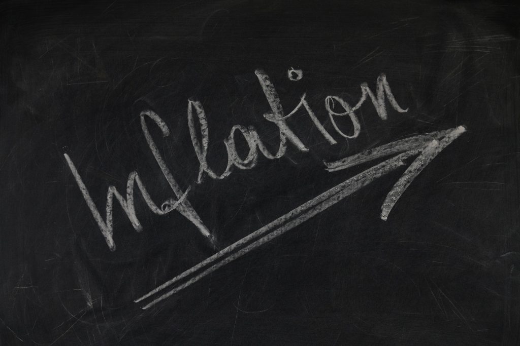 Das Wort Inflation mit Pfeil nach oben mit Kreide auf einer schwarzen Tafel geschrieben