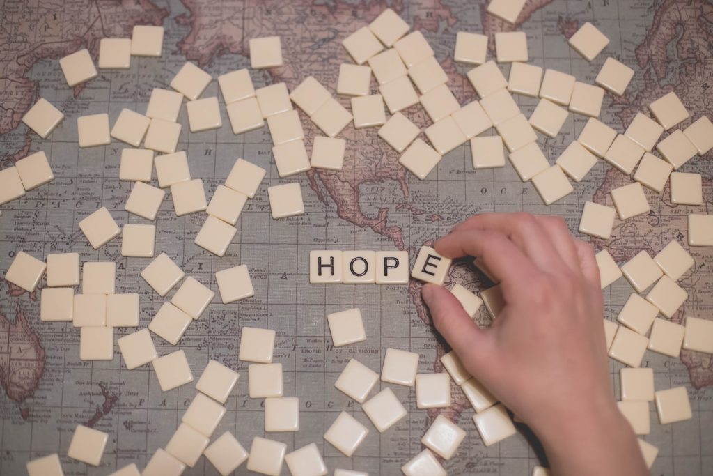 Das Wort Hope in Scrabbel-Buchstaben auf einer Weltkarte