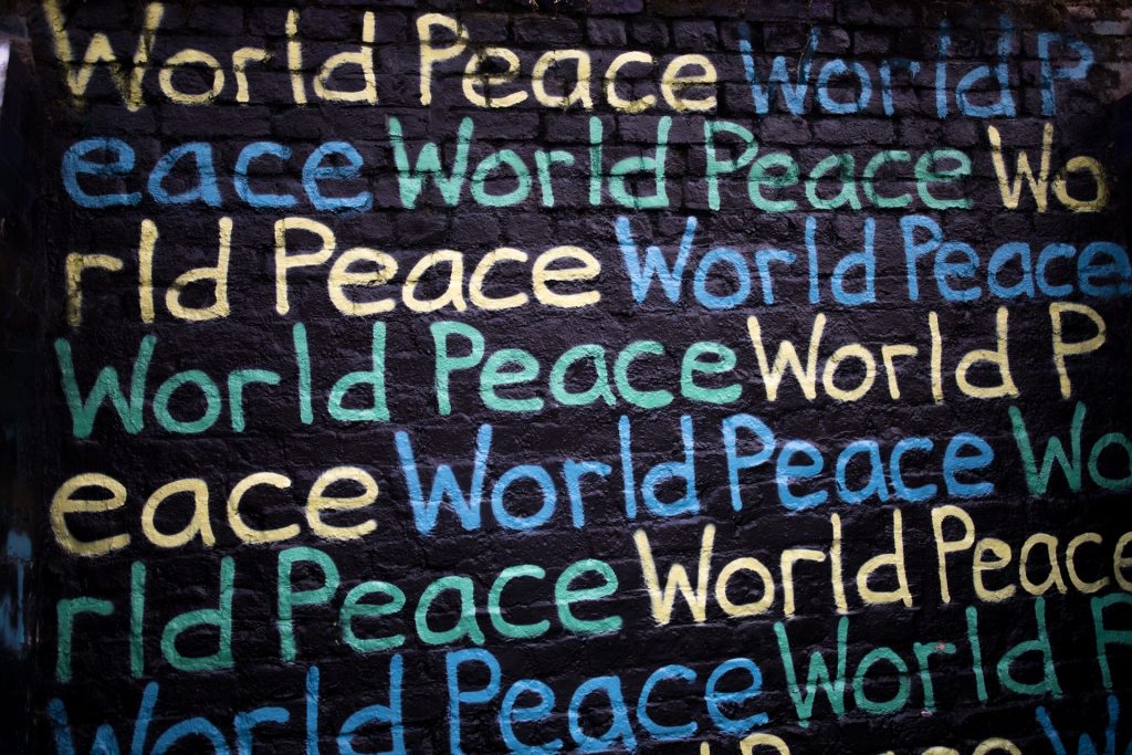 World Peace in verschiedenen Farben auf einer schwarzen Wand geschrieben