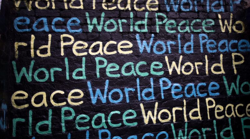 World Peace in verschiedenen Farben auf einer schwarzen Wand geschrieben
