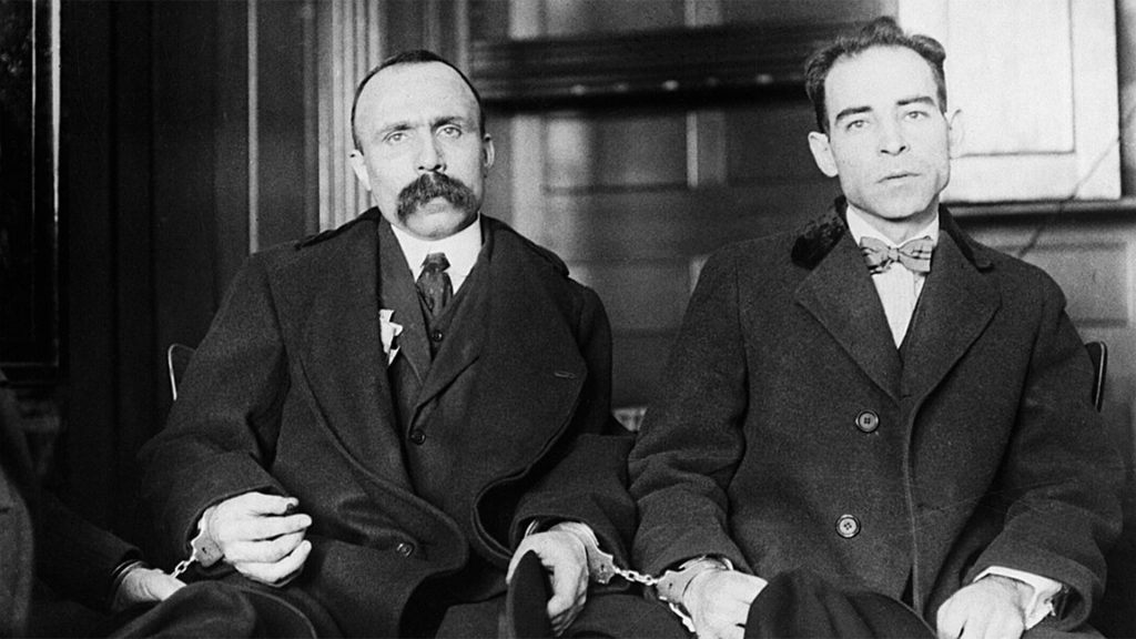 Sacco und Vanzetti in Handschellen, sitzend. Schwarz-weiß Foto.