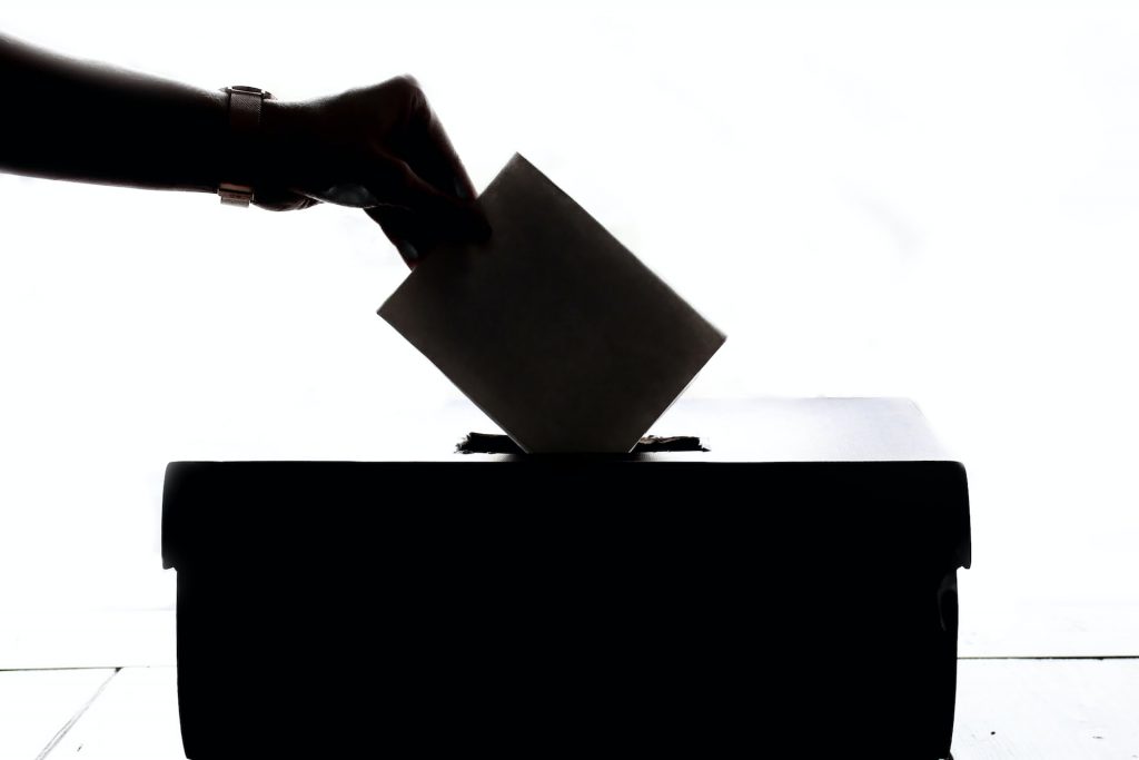Kuvert wird in eine Wahlurne geworfen, schwarz-weiß, Silhouette