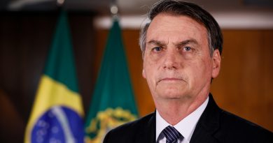 Jair Bolsonaro im schwarzen Anzug vor eine Brasilien-Flagge