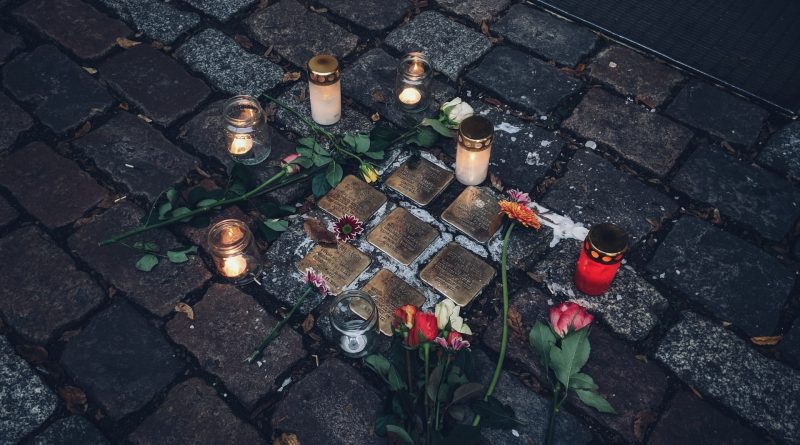 Gedenksteine an Opfer des Nationalsozialismus in Berlin, umrundet von Kerzen