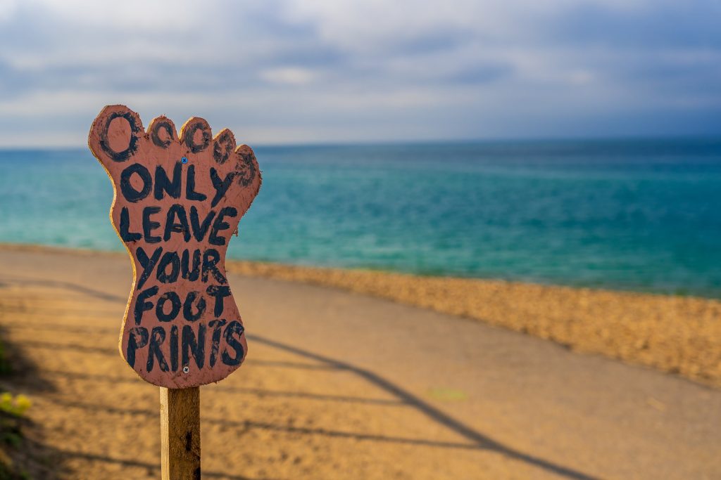 Schild in Fußform am Strand mit der Aufschrift: "Only leave your footprints"